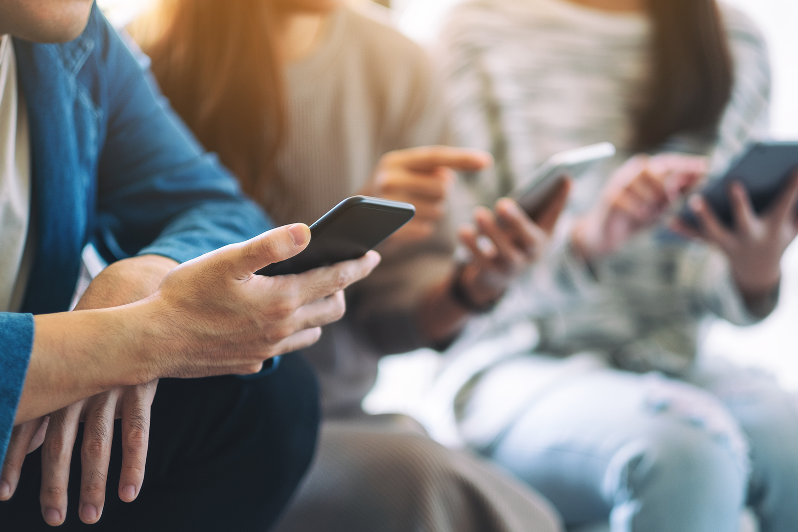 A group of people seated and engrossed in their smartphones.
