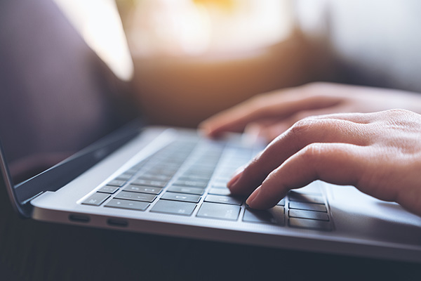 A person's hand is typing on a laptop keyboard.