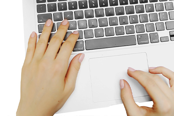 The image shows a person's hands typing on a laptop keyboard, with the laptop placed on a flat surface.