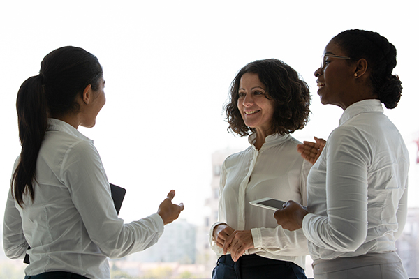 The image shows three individuals in a professional setting, engaged in conversation.