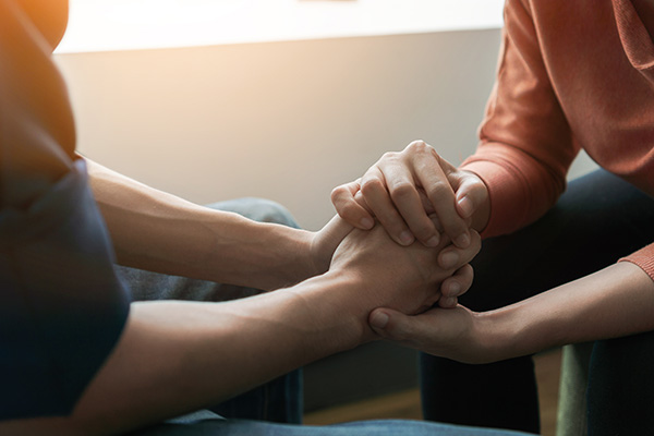 Two individuals holding hands, appearing to share a moment of connection or support.