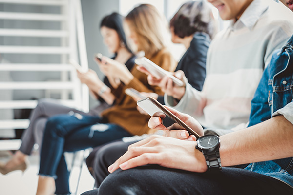 People sitting in a waiting area, engrossed in their smartphones.