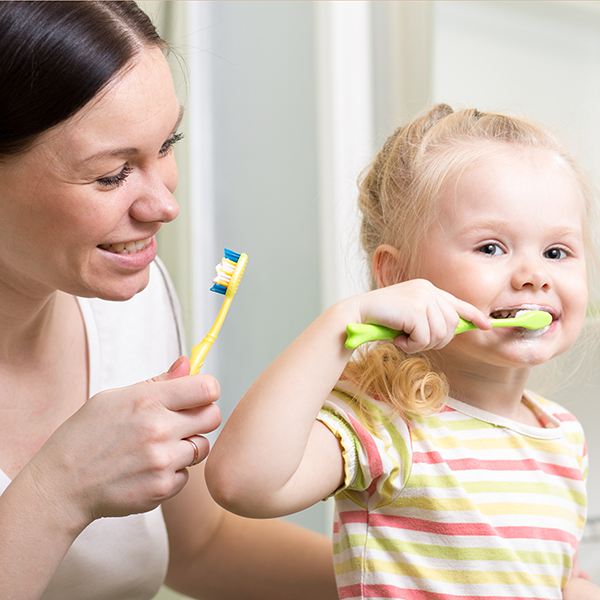A woman brushing a child's teeth, emphasizing oral hygiene.