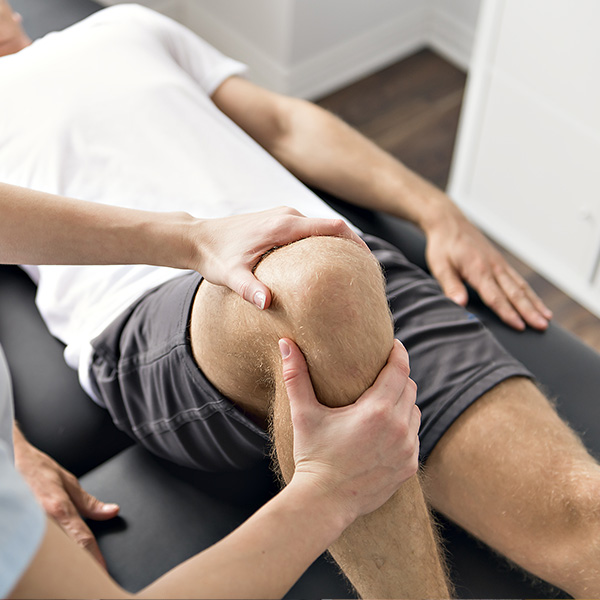 A person receiving physical therapy, with a therapist's hand on their knee.