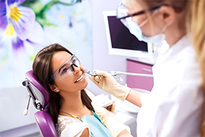 A dental professional is assisting a patient with a mouthguard on, in a modern dental office setting.