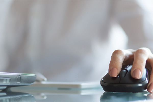 The image shows a person's hand using a computer mouse, with the focus on the mouse and the hand resting on it.
