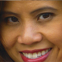 The image shows a smiling woman with dark hair and red lipstick, looking directly at the camera.